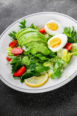 Salad avocado, boiled egg, tomato, green leaf lettuce, vegetable dish fresh gourmet food background on the table rustic food top view copy space vegetarian food