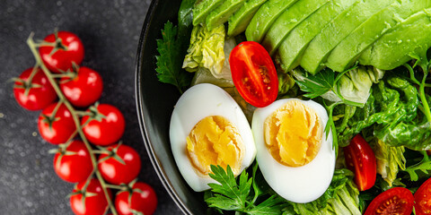 Salad avocado, boiled egg, tomato, green leaf lettuce, vegetable dish fresh gourmet food background on the table rustic food top view copy space vegetarian food