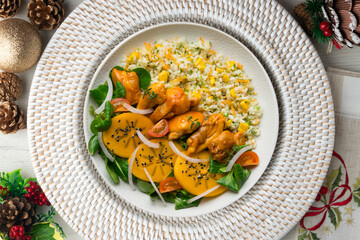 Combination plate with chicken, persimmon salad and rice. Top view table with christmas decorations.