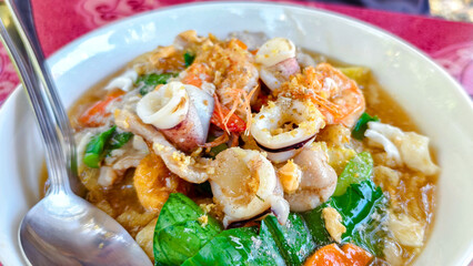 Seafood Dish: A culinary delight showcasing a medley of fresh seafood, artfully arranged in a rich sauce, enticing viewers with its vibrant colors and irresistible flavors.