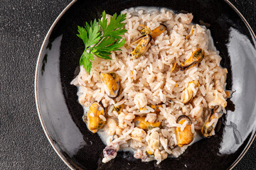Rice seafood risotto mussels, shrimp, prawn, rapan, squid vegetable dish fresh gourmet food background on the table rustic food top view copy space