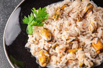 Rice seafood risotto mussels, shrimp, prawn, rapan, squid vegetable dish fresh gourmet food background on the table rustic food top view copy space