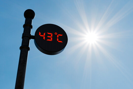 Street digital thermometer displaying a temperature of 43 degrees Celsius with blue sunny background. 