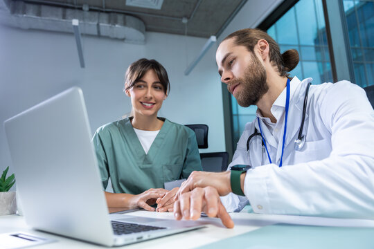 Female practitioner working with msn doctor in clinic using computer to analyze patient data