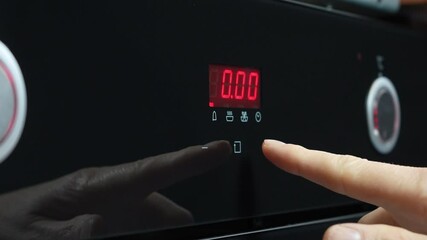 Close-up of a hand adjusting the digital display of a microwave oven. The man's index finger sets the timer on the electronic panel, displaying the time 0:05 in red. High quality 4k footage