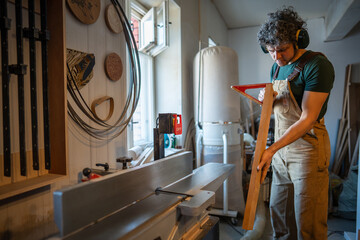 Joiner inspect wooden beam with care before starting final treatment on jointer machine. Precision...