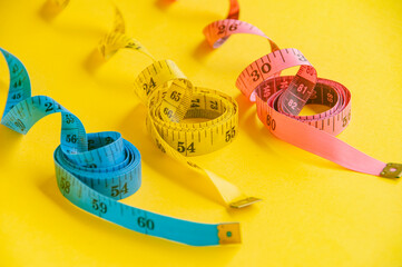 Precision and creativity symbolized by a blue, yellow and pink tape measure on yellow canvas....