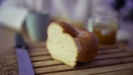Close-up of a freshly sliced loaf of bread on a wooden cutting board with a knife beside it. a...