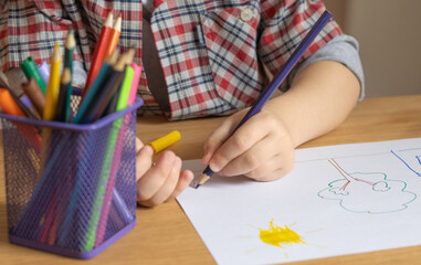 the child draws with felt-tip pens. children's hands close-up. pencils, sharpeners, sheet of paper. left hand