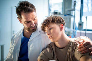 Compassionate doctor supporting anxious teenage patient before surgery.