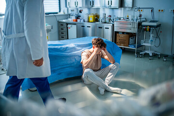 Depressed teenage patient sitting on hospital bed, waiting for doctor.