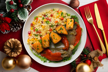Dish with baked salmon, peppers and couscous salad. Top view table with christmas decorations.