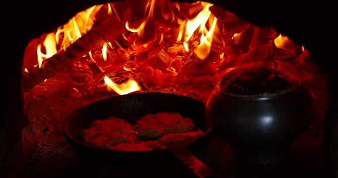 Traditional meal cooking in a real wood-fired oven. Flames flicker and food bakes slowly, capturing the essence of rustic home cooking and cozy warmth.