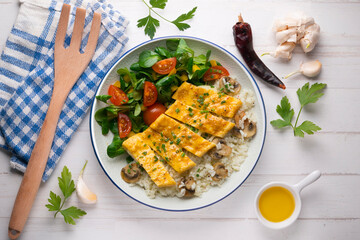 Dish with an omelet filled with cheese, rice and salad. Top view table.