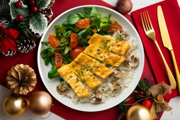Dish with an omelet filled with cheese, rice and salad. Top view table with christmas decorations.