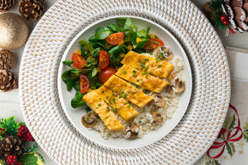 Dish with an omelet filled with cheese, rice and salad. Top view table with christmas decorations.