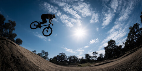 BMX Rider Mid Air Flip Dirt Ramp Extreme Sport Action Athlete Performing Trick Dynamic Movement Skillful Stunt Freestyle Biking Adrenaline Rush Outdoor Adventure Thrilling Ride
