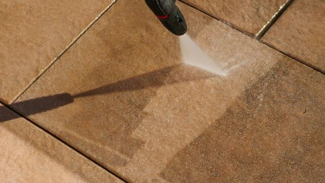 Cleaning balcony tiles with a high-pressure cleaner. Close-up