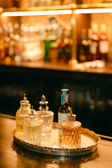 Elegant display of vintage spirits and liqueurs on a tray in a warmly lit bar