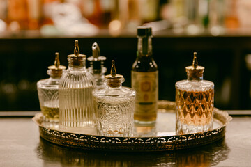 Elegant glass bottles on a bar tray filled with mixers at a cocktail lounge in the evening ambiance
