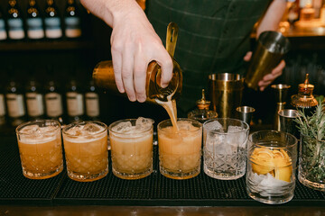 Expert bartender preparing a variety of cocktails during a busy night at a trendy bar in the city