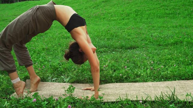 Girl gracefully executing an advanced yoga pose in a lush green park