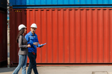 Businesswoman and logistic or shipyard engineer have a discussion or business due at container yard.