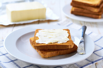 Crispy toast bread slices of piece of butter, on a white wooden table, selective focus.
