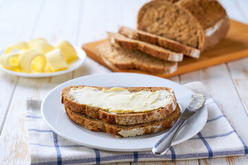 Fresh crusty buttered rye bread slices with butter  on a wooden table