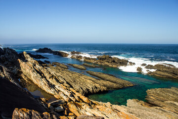 Tilted and Jagged rocks protecting the calm rock pools from the ocean waves along the Tsitsikamma Coast, South Africa