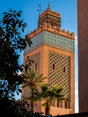 Kasbah Mosque minaret in Marrakesh, Morocco, also known as Moulay al-Yazid Mosque, framed by palm trees under blue sky, showcasing historic Islamic architecture, cultural heritage and vibrant scenery.