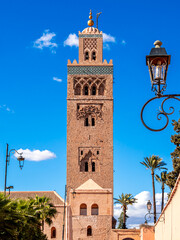 Koutoubia Mosque minaret in Marrakech, Morocco, standing tall under a blue sky surrounded by palm trees, showcasing historic Islamic architecture, cultural heritage and vibrant traditional cityscape.