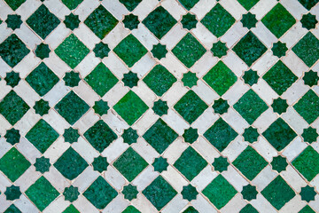 Traditional Moroccan green and white zellige mosaic with star and diamond patterns in Marrakesh, Morocco, handcrafted Islamic geometric tile artwork showcasing intricate design and cultural heritage.