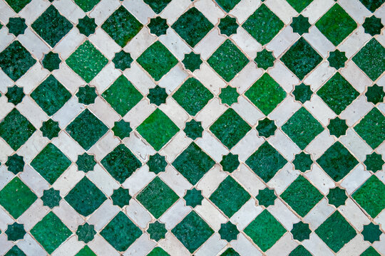 Traditional Moroccan green and white zellige mosaic with star and diamond patterns in Marrakesh, Morocco, handcrafted Islamic geometric tile artwork showcasing intricate design and cultural heritage.