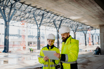 Engineers discussing construction plans using a tablet on site.