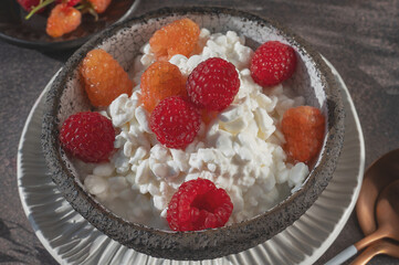 Creamed cottage cheese with raspberries. An easy healthy breakfast. A bowl filled with grainy, creamy cottage cheese is garnished with bright yellow and red raspberries