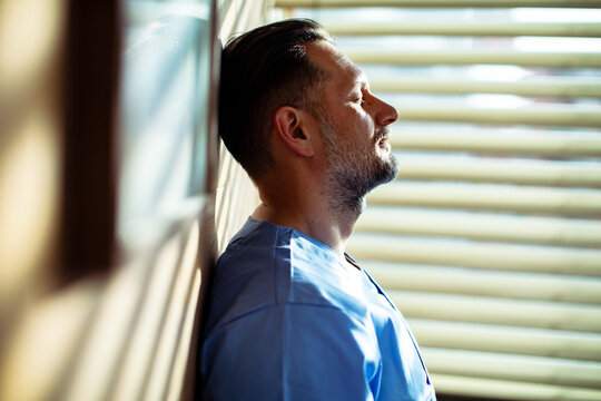 Tired doctor resting against wall after long shift