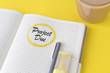 Open squared notebook with handwritten words project due circled in yellow marker, stylish blue...
