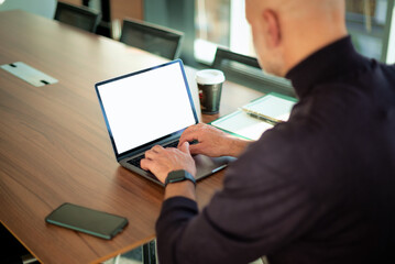 Rear view of man working with laptop at office desk