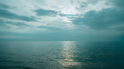 Obraz premium Bright morning on a calm ocean with fluffy clouds reflecting on the water surface in a serene coastal setting