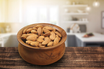 Wooden bowl full of almonds in a kitchen with blurred background