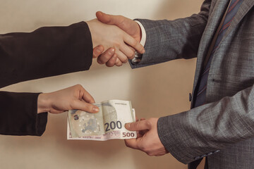 Handshake with euro banknotes being passed from one hand to the other. Bribe. Corruption.