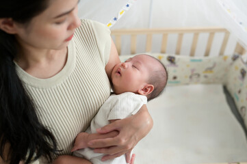 Mother Cradles Her Sleeping Baby in a Cozy Nursery During the Morning Light