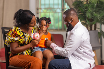 An African male pediatrician examines girl child heartbeat during routine checkup at the hospital.