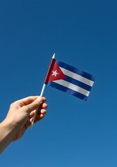 Pride in Identity—A Hand Holding the Cuban Flag Against a Clear Blue Sky
