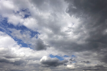 Heaven landscape with overcast storm weather with dramatic heavy gray rainy cumulus clouds and a little blue sky