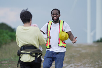 Construction worker in safety vest kissing partner while holding baby, symbolizing family support, love, work-life balance, and togetherness at outdoor worksite.