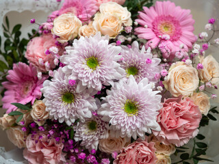 Close-up of a bouquet with pink roses, pink carnations, pink gerberas, white chrysanthemums, and...