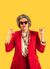 Senior influencer making call me gesture with hands wearing red suit and sunglasses