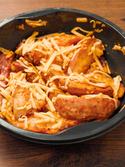 Ready made dish with wedges, garlic sauce and cheese in plastic tray on wooden table surface. Fast food made of high quality products ingredients. Lunch for cooking in microwave. Vertical image.